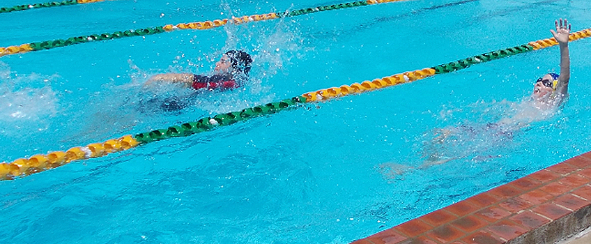 students competing in backstroke in the pool